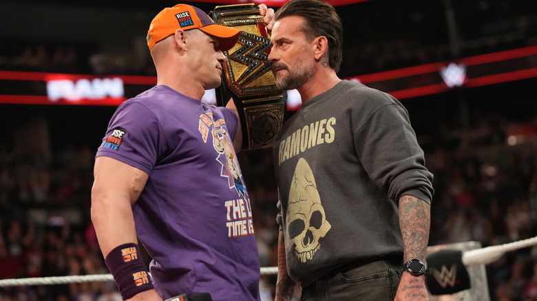 John Cena holds up the WWE Championship in front of CM Punk