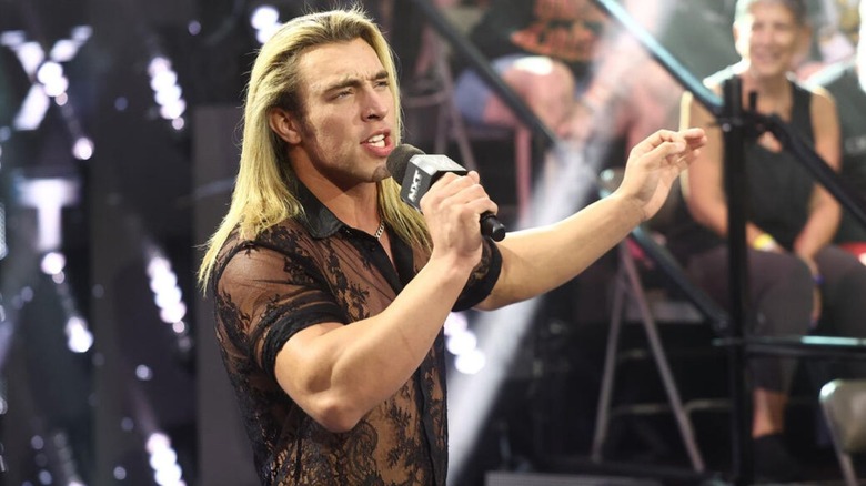 Tristan Angels cuts a promo in front of the WWE Performance Center crowd, as he looks to Zilla Fatu in the ring, during an episode of "WWE NXT."