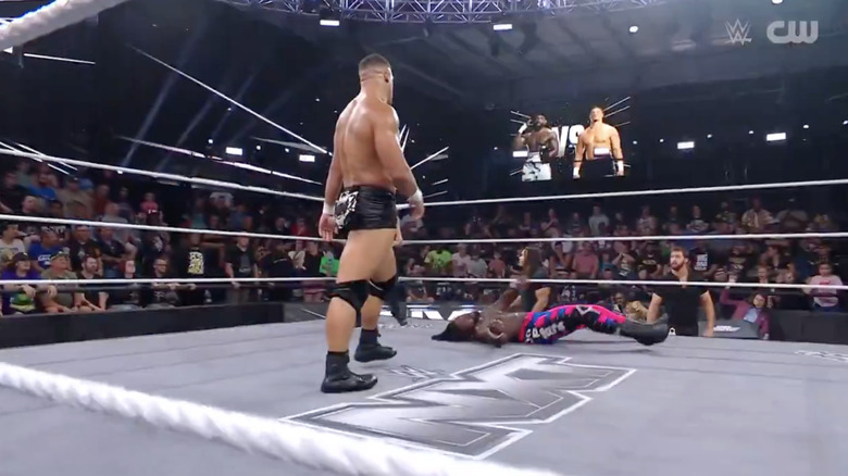 Lennox standing over Shugars in the ring as Griffin and James are on the outside