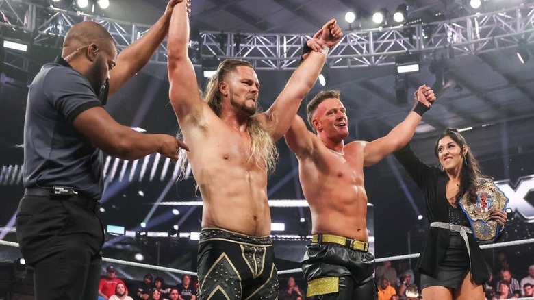 A referee holds up the arm of Lexis King, alongside Channing 