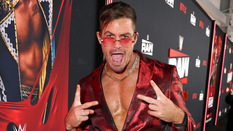 Grayson Waller in a red jacket and sunglasses giving two peace signs
