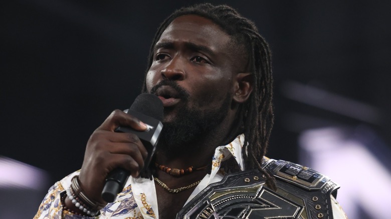 Oba Femi holding a mic and the WWE NXT Championship