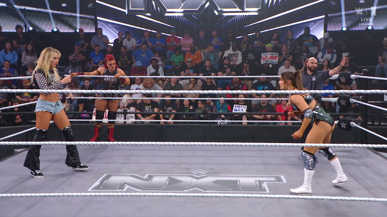 Ruca and Grey in the ring as Zaria watches from the apron