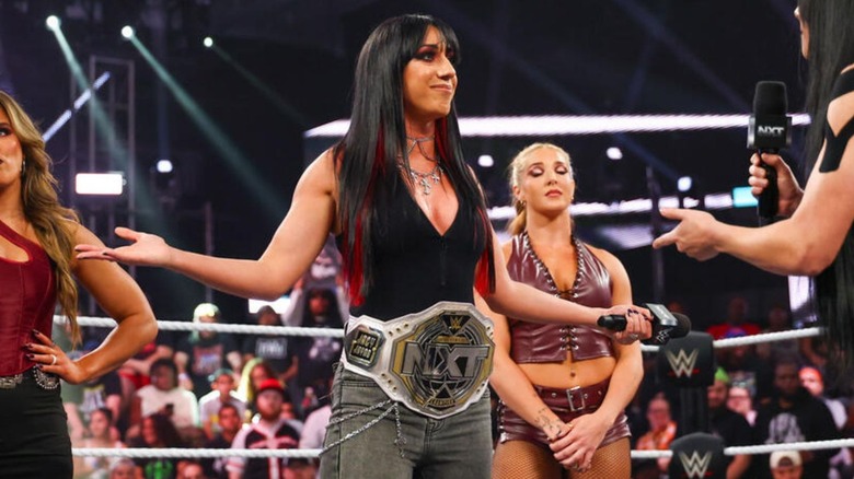 Jacy Jayne stands in the ring backed by Fatal Influence, arms spread, challenging Tatum Paxley, during an episode of "WWE NXT."