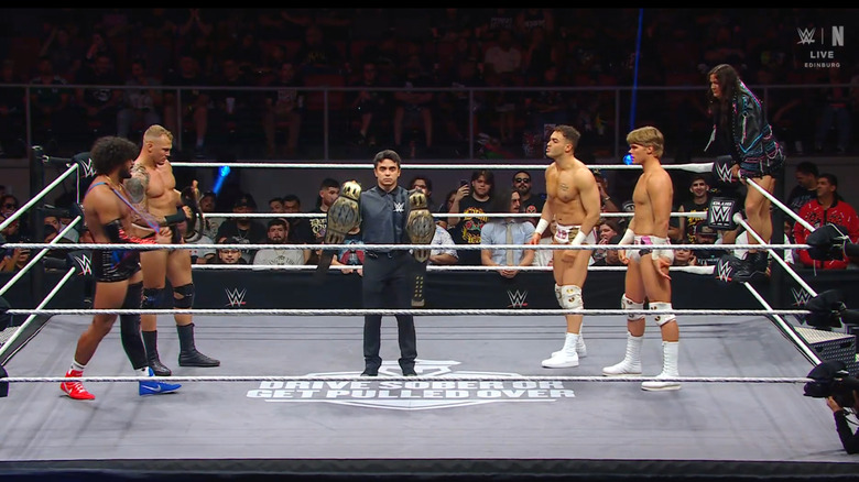 All four men in the ring as the referee has the NXT Tag Team Championship belts in hand