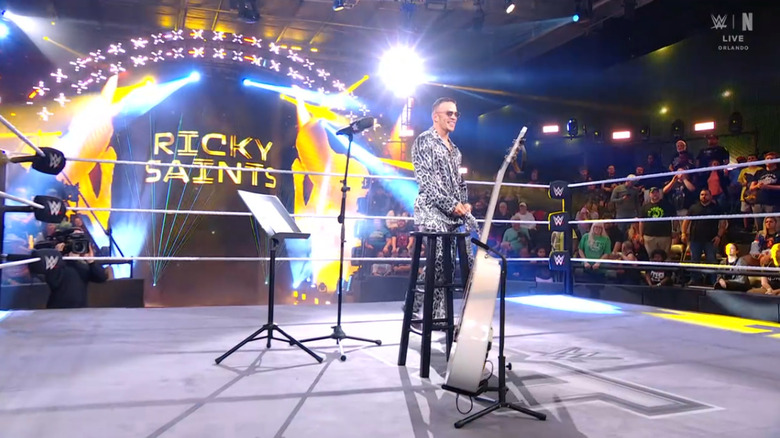 Saints in the ring with his guitar and stool