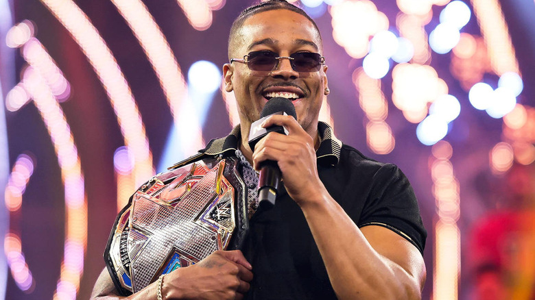 Carmelo Hayes carrying the "NXT" Championship on his shoulder