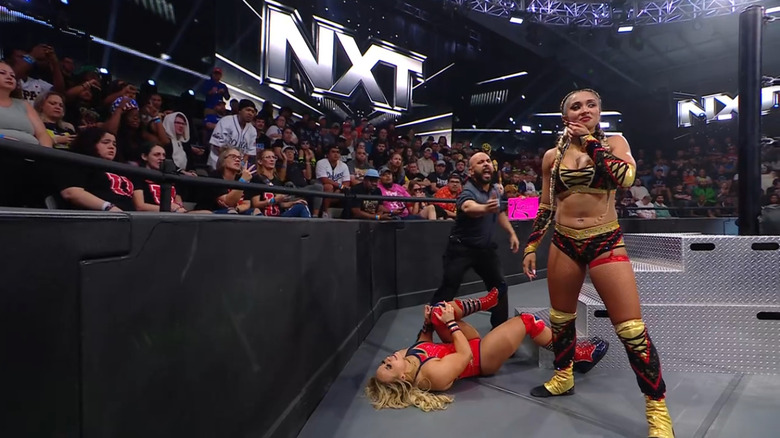 Jordan standing over Grace on the outside while Grace grabs her knee