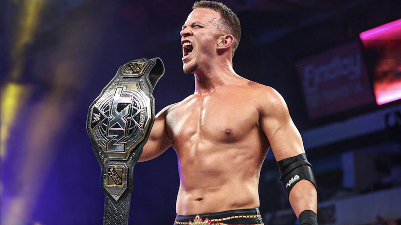 Saints holding up his NXT Championship belt