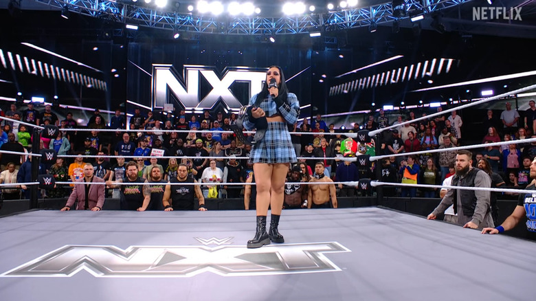Ava in the ring surrounded by the NXT men's roster