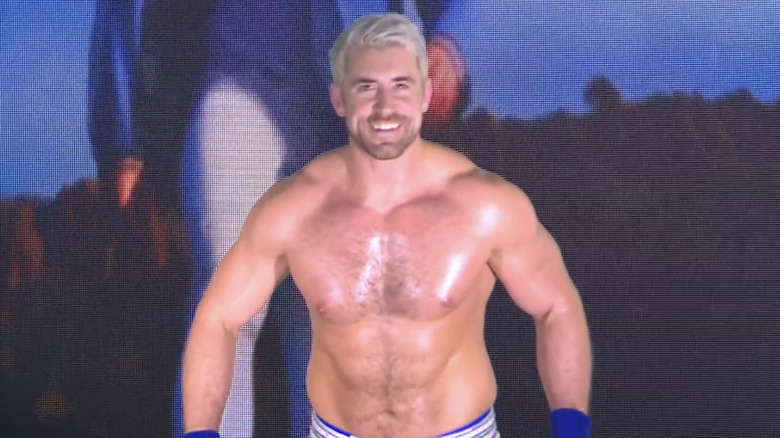 An oiled-up Joe Hendry flashes his pearly whites during his iconic entrance.