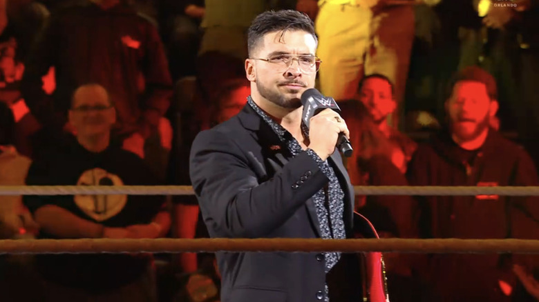 "All Ego" Ethan Page takes to the microphone while holding his "NXT" North American Championship.