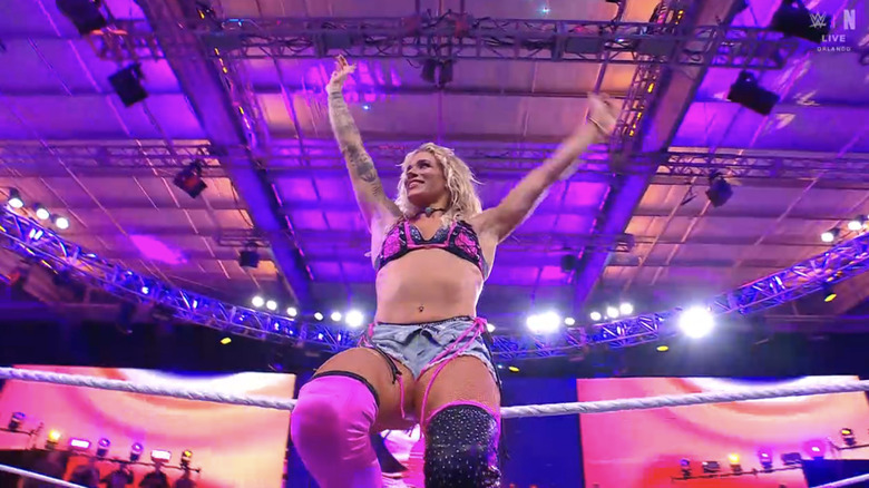 Sol Ruca waves as she sits on the top rope.