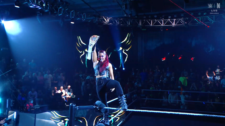 Zaria holding up her Women's North American Championship belt as she poses on the ropes