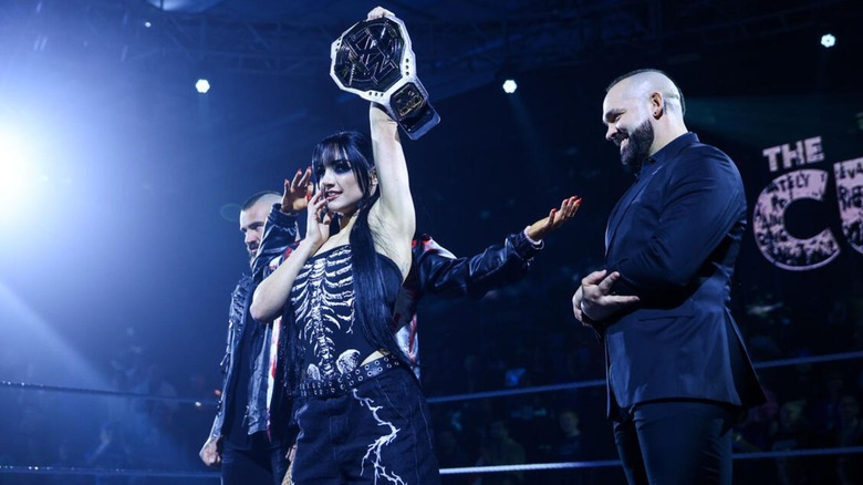 Tatum Paxley holds up the NXT Women's Championship in the ring, as Shawn Spears and The Culling look on during an episode of 