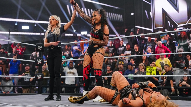 A referee raises the hand of Jaida Parker after her victory of Nikkita Lyons, who lays in the ring, during an episode of 