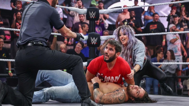 Johnny Gargano looks to the referee after pinning Shiloh Hill, and wife Candice LeRae looks to hug him from behind, during an episode of 