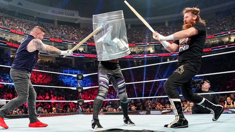 Kevin Owens and Sami Zayn batter an opponent in a trash can