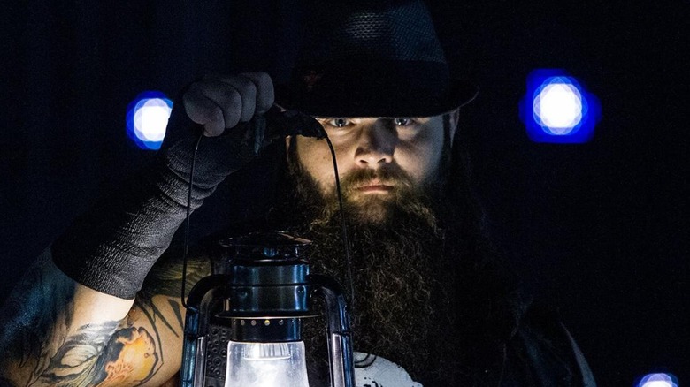 Bray Wyatt standing behind the light of his lamp ahead of a segment on WWE television.