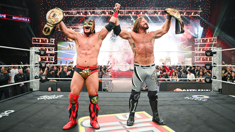 AJ Styles and Dragon Lee with their hands raised