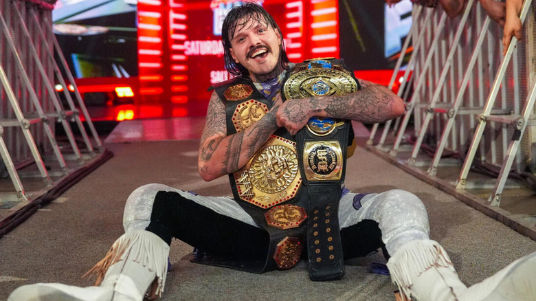 Dominik Mysterio sits on the entrance ramp with both the AAA Mega Championship and the WWE Intercontinental Championship.