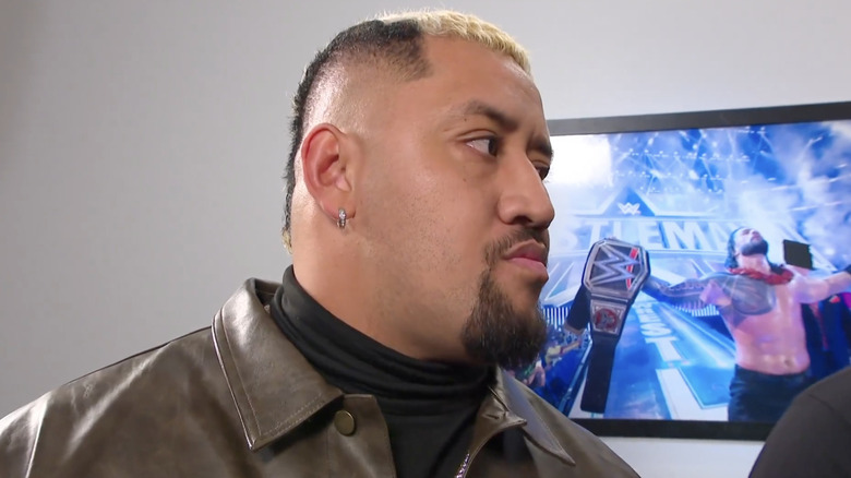 Sikoa with a picture of Roman Reigns behind him