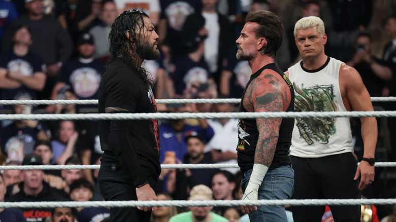 Cody Rhodes watches as Roman Reigns and CM Punk stare each other down