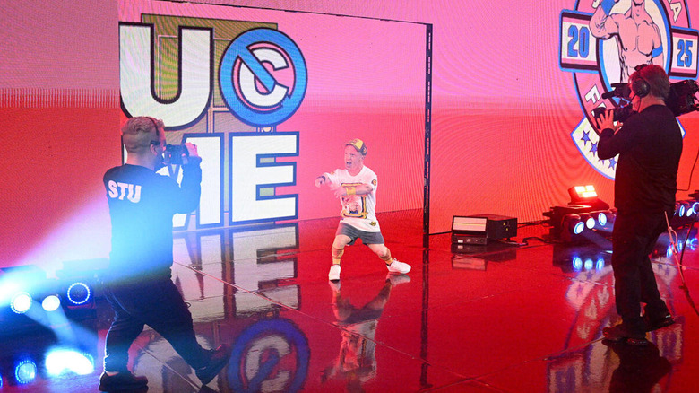 John Wee-na makes an entrance, with a little camera guy in front of him.