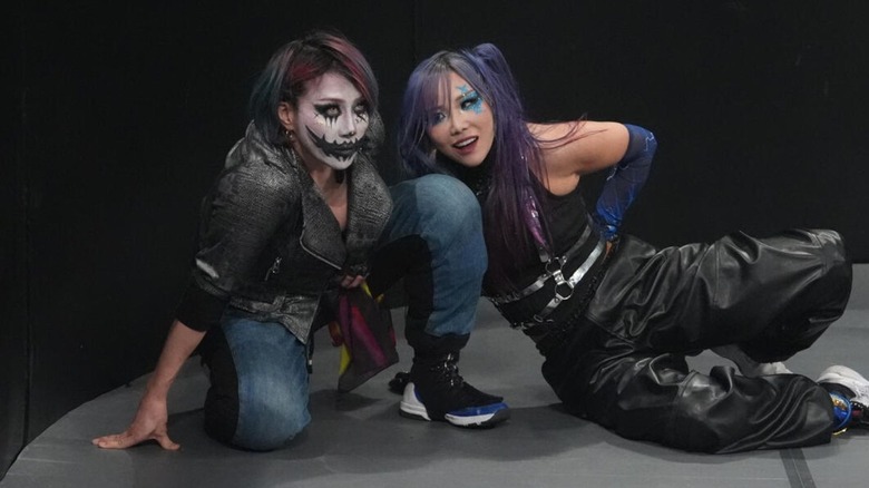 The Kabuki Warriors sit ringside, Asuka glaring into the ring, with Kairi looking at her partner, during an episode of "WWE Raw."