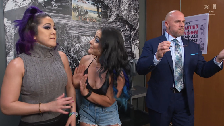 Lyra Valkyria attempts to calm down Bayley as Adam Pearce looks away in exasperation.