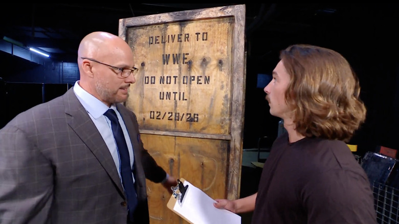 Adam Pearce and Eli in front of a crate on "WWE Raw"