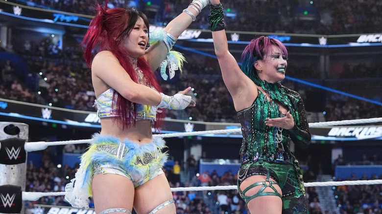 IYO SKY and Asuka hold up each others hands in the ring and gesture in respect to one another after their match at WWE Backlash.