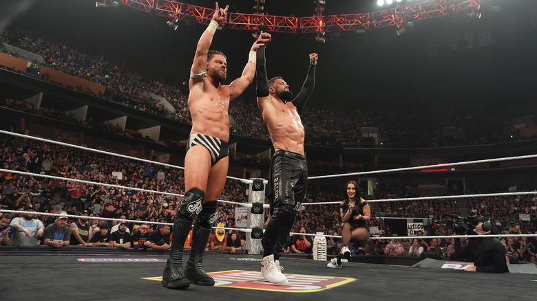 Roxanne Perez looks on as Finn Balor and JD McDonagh celebrate a tag team win on "WWE Raw"