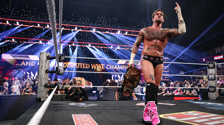 CM Punk pointing upward while holding the WWE Championship