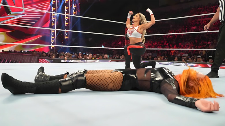 Trish Stratus kneels and flexes with Becky Lynch down