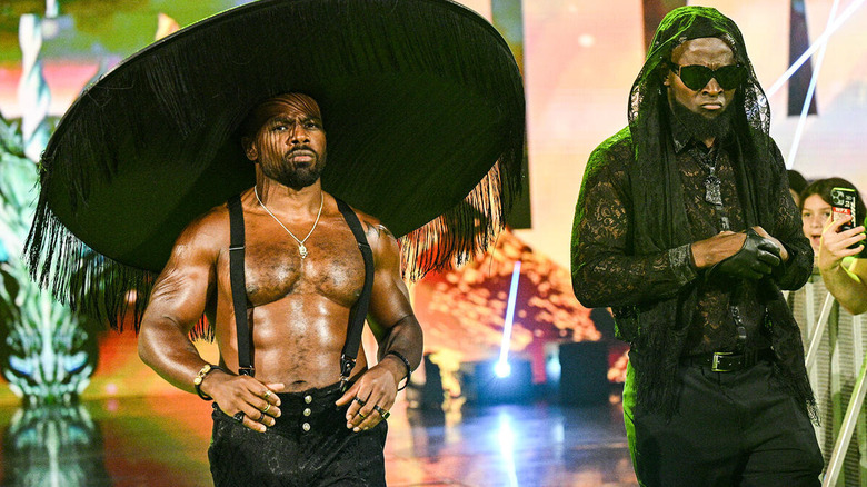 Xavier Woods, in a comically large hat, and Kofi Kingston, in matching mourning attire, make their entrance on "WWE Raw."