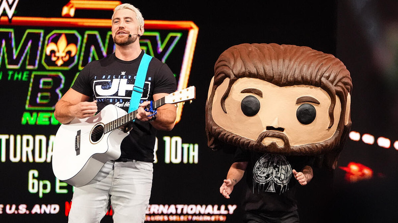 Joe Hendry playing guitar beside a giant JD McDonagh Funko Pop