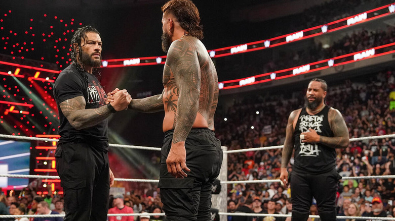 Jey Uso and Roman Reigns talk as Jimmy Uso watches on