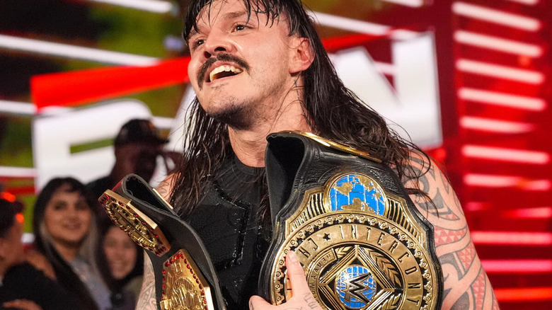 Dominik Mysterio smiles while holding his titles on "WWE Raw"