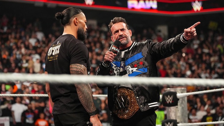 CM Punk pointing while speaking to Roman Reigns on 