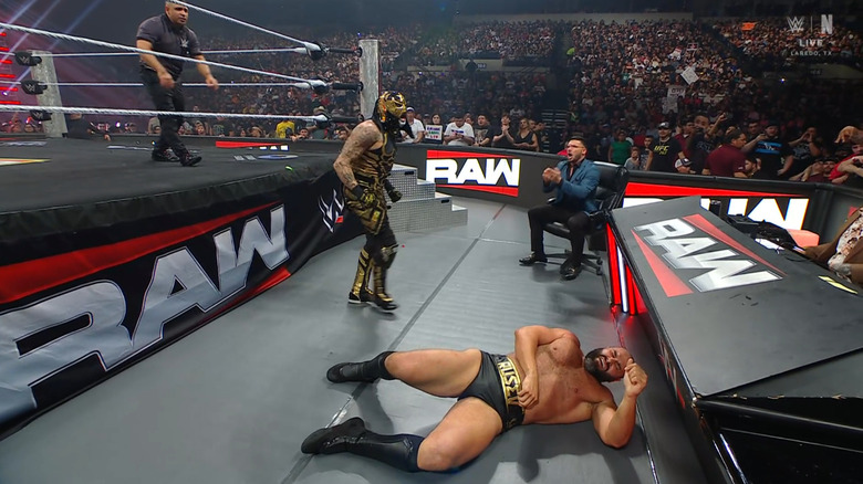 Penta standing over Rusev on the outside as Page watches