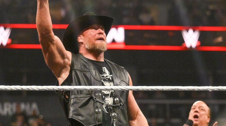 Brock Lesnar poses in the ring as Paul Heyman cuts a promo on an episode of 