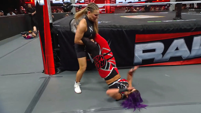 Nattie about to catapult Bayley into the ring post as Asuka lays on the outside