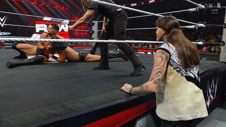 Dominik watching from the outside as Balor has a submission cinched in on McDonagh