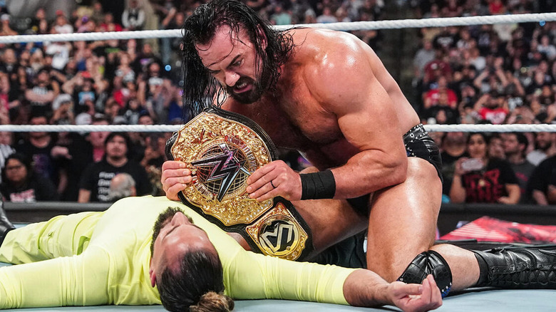 Drew McIntyre holding the WWE World Heavyweight Championship on top of Seth Rollins' body