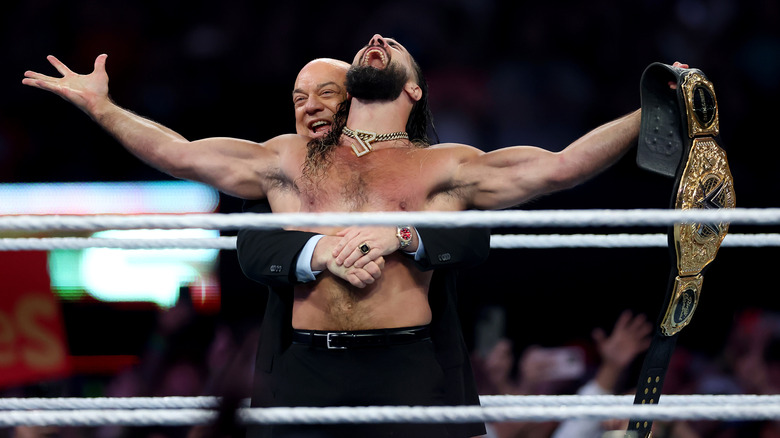 Paul Heyman hugging Seth Rollins from behind