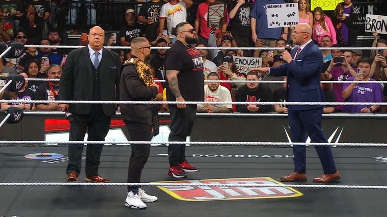 Heyman, Breakker, and Reed in the ring staring down Pearce