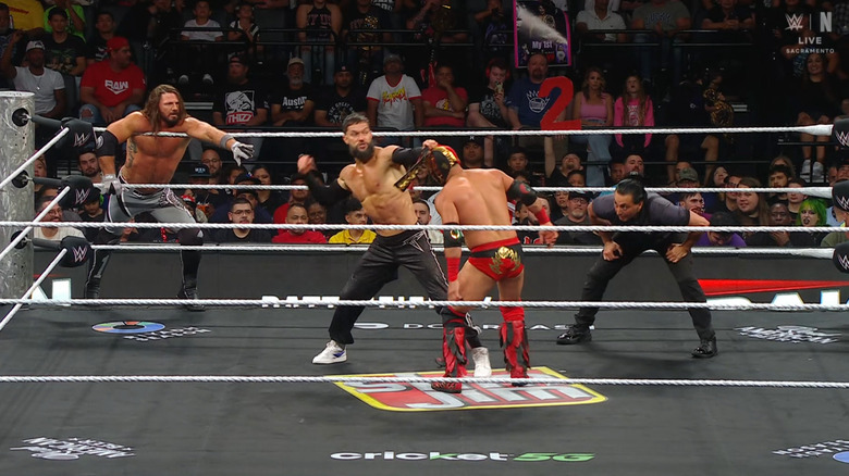 Styles looking to tag in as Balor fires off right hands on Lee