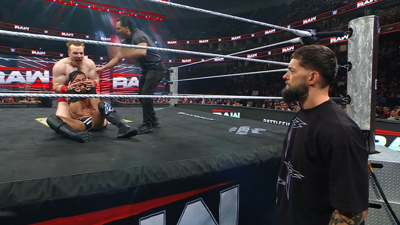 Sheamus with a submission cinched in on McDonagh as Balor watches from the outside
