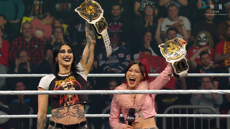Ripley and SKY holding up their Women's Tag Team Championship belts